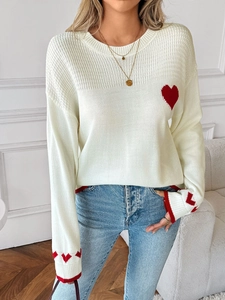 Detail of red heart jacquard and contrast stitching on a cream knitted sweater