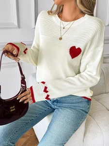 Close-up of knit texture with red heart pattern and striped cuffs on cream sweater