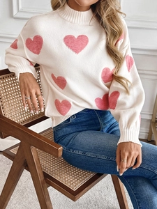 Detail of soft cream knitted sweater featuring a large pink heart and high neck design