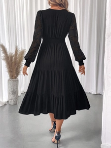 Detail of elegant black dress showing floral embroidery on sheer sleeves and tiered skirt
