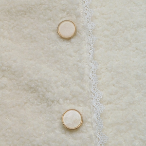 Detail der Fleecejacke mit Spitzenbesatz und Marmorknöpfen mit goldenem Rand