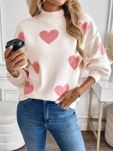 Detail of white knit sweater featuring pink heart jacquard pattern and ribbed collar