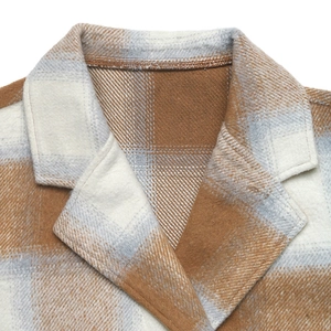 Detailed view of plaid wool coat collar with tan and blue tartan textured fabric