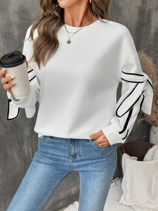 Detail of white sweatshirt sleeve featuring a 3D bow with black contrast edges