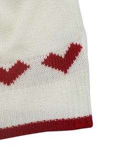 Close-up of the heart pattern knitting texture and red ribbed edge on this white sweater