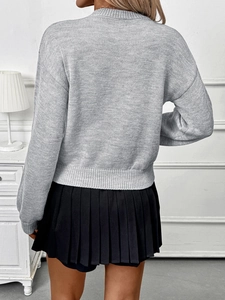 Back view of a grey crew neck knitted sweater and black pleated skirt in a cozy room