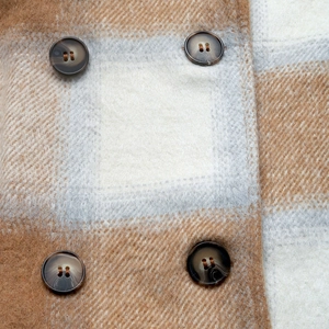 Detail of plaid wool coat showing brown checkered fabric and marble pattern buttons