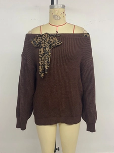 Detailed close-up of brown knit sweater featuring leopard print bow and ribbed cuffs