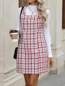 Close-up of red and white plaid tweed pinafore dress styled with a white turtleneck sweater