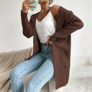Dettaglio di un lungo cardigan in maglia marrone con trama a coste verticali e tasche laterali