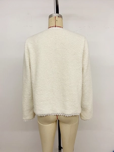 Detailansicht der cremefarbenen Teddy-Jacke mit filigraner weißer Spitzenborte am Saum