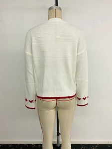 Detail of white knit sweater back featuring red heart motifs and striped ribbed cuffs