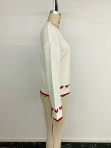 Detailed side view of cream knit sweater showing red heart motifs and ribbed cuffs