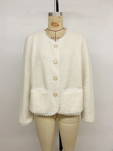 Detail der weißen Sherpa-Jacke mit feinem Spitzenbesatz und goldenen Knöpfen