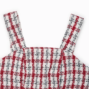 Close-up of red and white plaid tweed fabric texture on a square neck dress strap