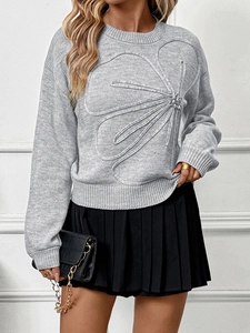Detail view of a light grey knit sweater featuring 3D floral accents and drop shoulders