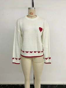 Detail of the white crewneck sweater with red heart jacquard pattern and ribbed cuffs