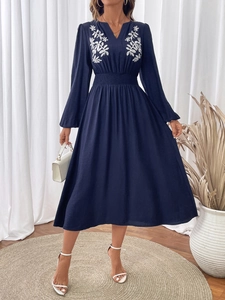 Détail de l'élégant décolleté en V avec broderie florale blanche sur robe marine à manches