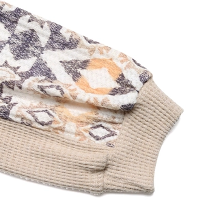 Détail de la manche à motif ethnique avec poignet en maille côtelée beige sur haut chic
