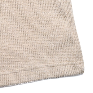 Gros plan sur le tissu gaufré beige montrant des coutures de qualité et une texture maille