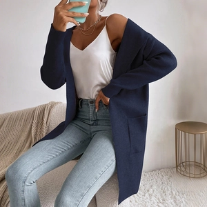 Dettaglio di un cardigan lungo in maglia blu scuro con ampie tasche anteriori e trama a costine