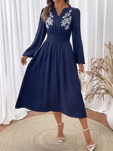Détails de broderie florale blanche sur robe longue bleu marine à col en V et manches
