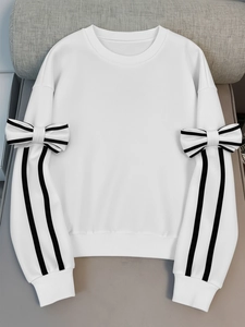 Detail view of white sweatshirt featuring black and white striped bows on the sleeves