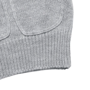 Detail view of light gray knit sweater ribbed hem and flat pocket stitching texture