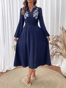 Détail de la broderie florale sur une robe midi bleu marine à manches longues