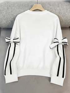 Detail of white sweatshirt featuring shoulder ribbons and black stripes on sleeve