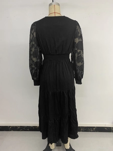 Detail of elegant black dress showing floral lace sleeves and tiered cake skirt texture