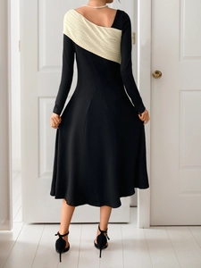 Rear view of an elegant black and white color-block long-sleeved midi dress with a waist tie