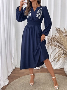 Détails de broderie florale blanche sur une robe bleu foncé à manches longues et col en V