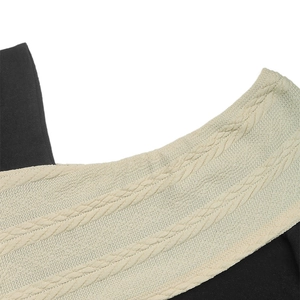 Detail of cable-knit texture and contrast black panels on a knit sweater