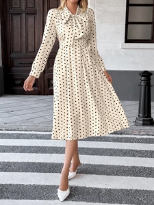 Détail d'une robe midi vintage à pois avec col à nœud papillon et manches longues