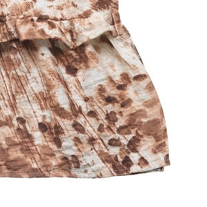 Detailed view of brown and white tie-dye fabric with ruffle textures and fine stitching