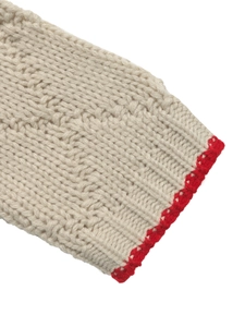 Gros plan d'un pull en maille beige avec une bordure contrastée rouge faite à la main