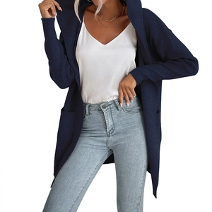 Dettaglio del cardigan in maglia blu scuro con tasche, top bianco e jeans azzurri