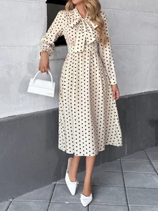 Détail d'une robe vintage à pois avec encolure à nœud papillon et taille cintrée chic