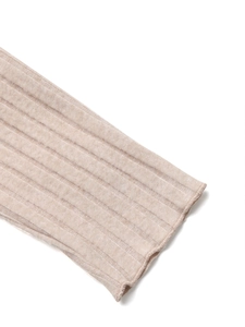 Detail view of beige ribbed knit fabric showing texture on sleeve and hemline
