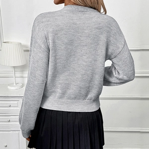 Women's grey knit sweater with textured jacquard and black pleated skirt outfit