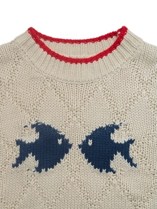 Détail du col rond avec bordure rouge et jacquard de poisson bleu sur le pull en maille beige