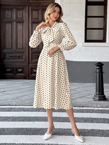 Détail d'une robe midi beige vintage à pois noirs avec un col à nœud élégant