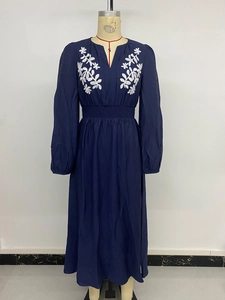 Détail de la robe bleu marine à col en V avec broderie de feuilles blanches et taille élastique
