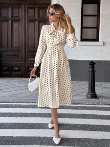 Détail du col à nœud et du motif à pois sur cette robe mi-longue à manches longues