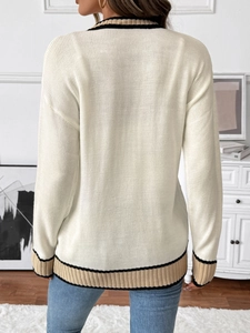 Detail view of the back of a cream knitted cardigan with striped ribbed hem and cuffs
