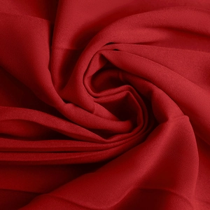 Close-up of pleated deep red plain weave fabric showing detailed textile texture and drape