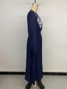 Détail de broderie florale blanche sur robe longue bleu marine à manches longues