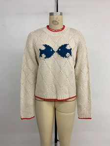 Détail du pull en maille avec motif de poisson jacquard bleu et bordures contrastées rouges