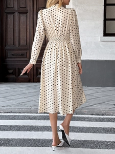 Vue arrière d'une robe mi-longue beige à pois avec manches longues et taille plissée